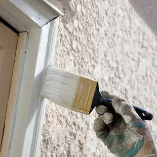 Fensterrahmen - Nahaufnahme eines Malers, der am Außenfenster mit einem Pinsel Lack aufträgt.