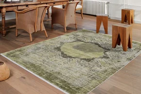 Illustration - Ihr Experte für schönes Wohnen - Ein grüner Teppich im orientalischen Muster liegt im Esszimmer auf einem Holzboden.